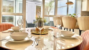 Un comedor con una mesa redonda preparada para cuatro personas, ventanas amplias y vistas al exterior.
