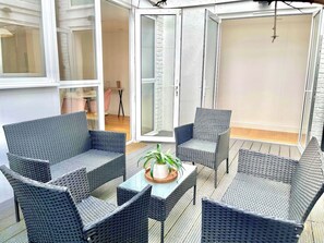 Una habitación con mobiliario de mimbre, una mesa de vidrio y una planta en maceta.