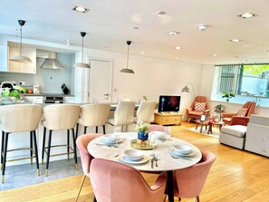A modern living room with a dining area, a television, and a kitchen in the background. - 3-bdr Holloway Flat W/ Patio near emirates stadium (Greater London)