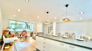 Una cocina moderna con armarios blancos, una isla central e iluminación colgante.