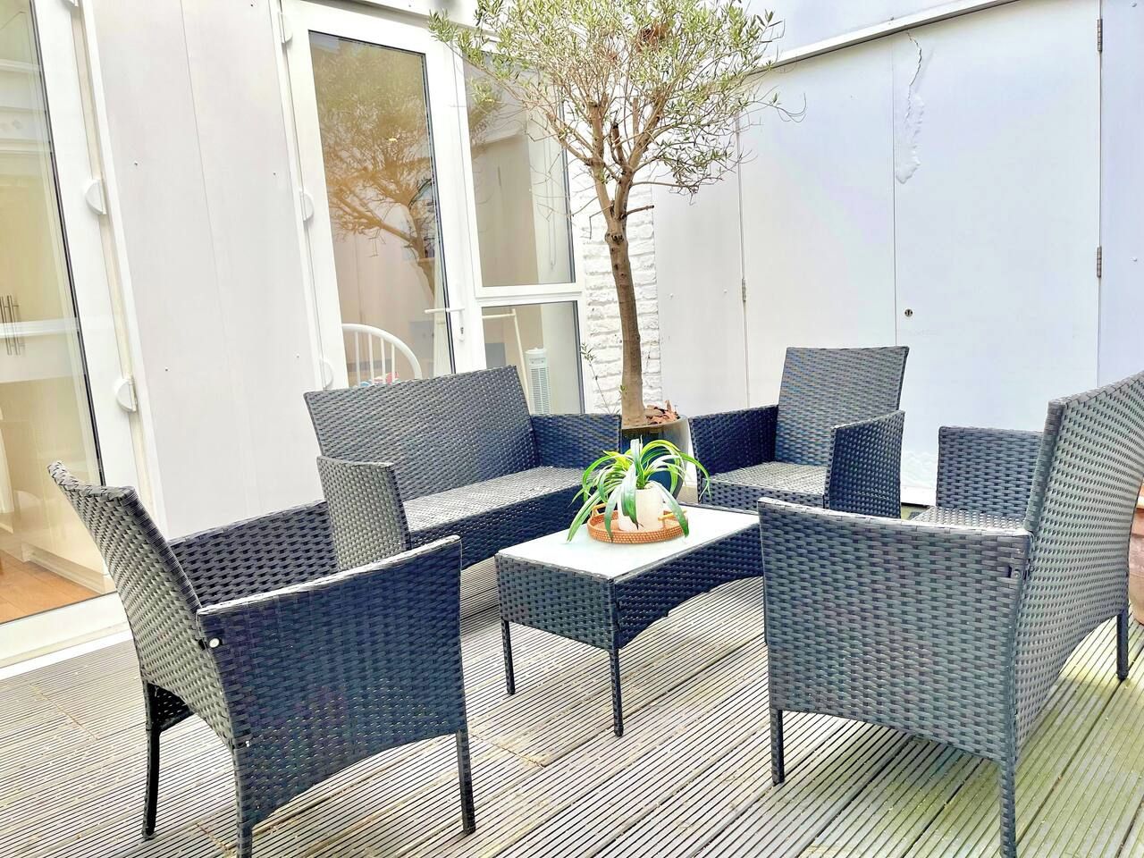 A patio with wicker furniture and a potted plant.