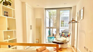 Un dormitorio moderno con cama, una silla, una estantería y un ventanal grande.