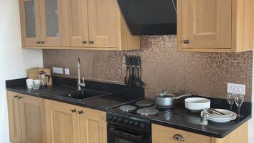 Cozinha com armários de madeira, fogão preto e painel de azulejos.