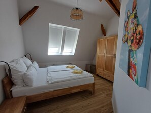 A bedroom with a wooden bed, a window, a wardrobe, and a painting on the wall.