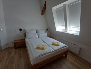 A bedroom with a bed, bedside tables, a window, and a radiator. - Posthus Apartment 304 - completely renovated, close to the beach and central (Borkum)
