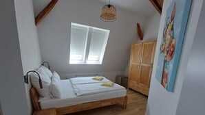 Een slaapkamer met een houten bed, een raam, een kledingkast en een schilderij.