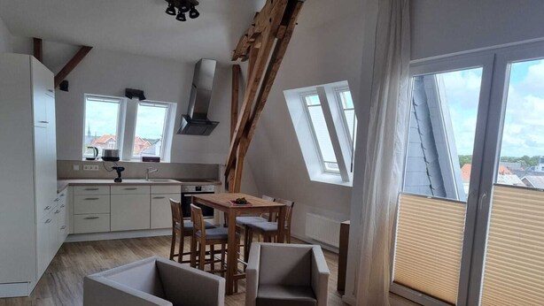 Een modern loft appartement met keuken, eethoek en grote ramen met uitzicht op de stad.