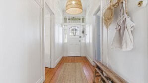 A hallway with a wooden floor, white walls, a white door with a glass panel, and a hanging light fixture. - The Anchor House - Perfect Gem in the centre of Port Fairy (Port Fairy)