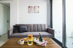 Ein modernes Wohnzimmer mit einem grauen Sofa, einem Holztisch mit einer Zeitschrift, einer Tasse und einem Glas Zitronenlimonade.