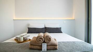 Una cama bien hecha con toallas enrolladas, una bandeja con tazas y una nota de agradecimiento.
