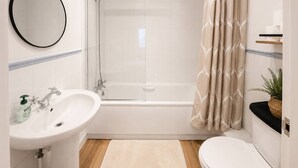 A bathroom with a bathtub, a sink, a toilet, a shower, and a mirror. - West Kensington Apt + Garden/wifi near earls court (London)