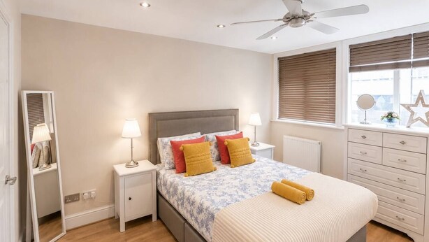 A bedroom with a bed, bedside tables, a dresser, a mirror, and a ceiling fan. - West Kensington Apt + Garden/wifi near earls court (London)