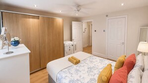 A bedroom with a bed, a wardrobe, a mirror, a lamp, and a washing machine. - West Kensington Apt + Garden/wifi near earls court (London)