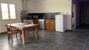 Une cuisine moderne avec une table et des chaises, un four à micro-ondes, un réfrigérateur et des armoires en bois.