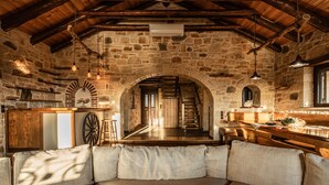 Un intérieur rustique en pierre, avec un escalier en bois, un canapé et un coin bar.