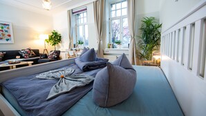 Un dormitorio ordenado con cama, mesitas de noche, lámpara y ventana con cortinas.