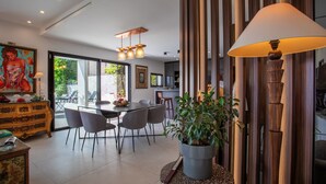 A modern dining area with a large table, chairs, and a potted plant. - Villa Les Sources VI4245 By Riviera Holiday Homes (Niza)