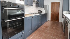 Una cucina moderna con forno integrato, microonde e piano cottura a gas.