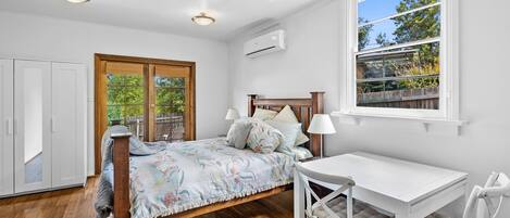 A bedroom with a bed, a desk, and a window.