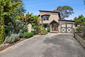 Une maison à deux étages avec une allée en gravier et un garage.