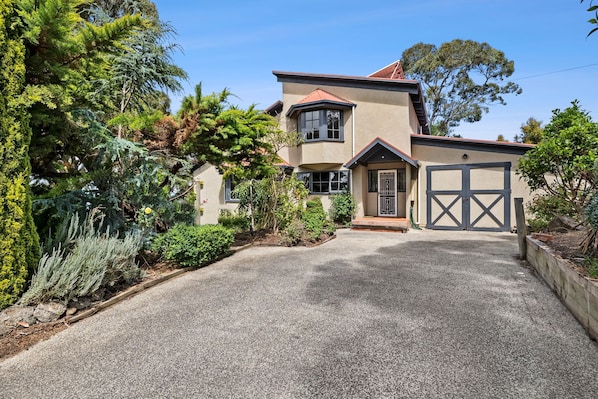 A two-story house with a gravel driveway and a garage.