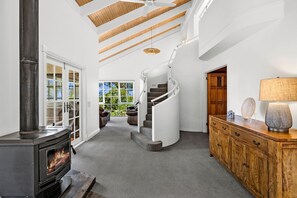 Un intérieur moderne avec une cheminée, un escalier en bois et une vue sur la verdure environnante.