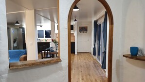 A hallway with wooden flooring, a white wall, and a wooden archway. There is a dining area with a table and chairs, and a kitchen visible in the background. - Single-storey house with private garden and terrace. ANCV, Pets allowed (ST LUNAIRE)