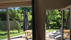 A room with a large window, a wooden table, and a bench outside. - Single-storey house with private garden and terrace. ANCV, Pets allowed (ST LUNAIRE)