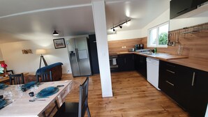 A modern kitchen with wooden flooring, a dining area with a table set for four, and a refrigerator. - Single-storey house with private garden and terrace. ANCV, Pets allowed (ST LUNAIRE)
