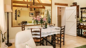 A dining area with a large mirror, wooden chairs, a table set for four, and a vase of flowers. - Swallows Barn (Chesterfield)