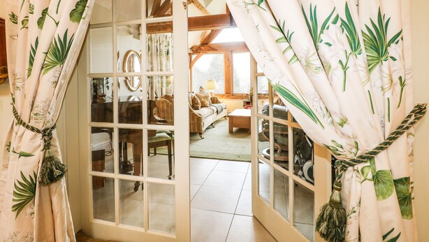 A cozy room with a wooden ceiling, a sofa, and a window with curtains. - Swallows Barn (Chesterfield)
