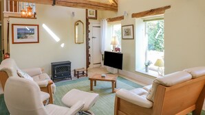 A cozy living room with a fireplace, comfortable seating, and a television. - Swallows Barn (Chesterfield)
