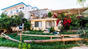 A residential building with a balcony, a garden area with plants and a wooden fence, and a clear sky. - Eucalyptus Pension (Kas)