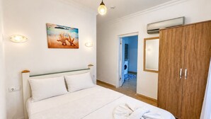 A bedroom with a bed, a wooden wardrobe, a painting, and an air conditioning unit. - Eucalyptus Pension (Kas)