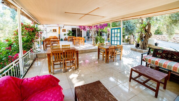 A covered patio area with wooden furniture, including tables and chairs, and a bench. - Eucalyptus Pension (Kas)