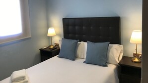 Et hotelværelse med en stor seng, to sengeborde, to lamper og et vindue.