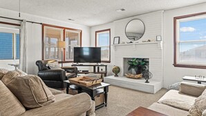 A living room with a fireplace, a television, and comfortable seating. - Dawn Patrol 4 Bedroom Home in Kitty Hawk (Kitty Hawk)