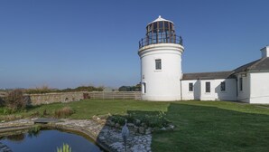 A lighthouse with a circular base and a domed top, surrounded by a grassy area and a small pond. - Kimberlin (Portland)