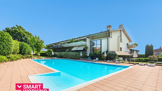 Um edifício moderno com piscina, área de estar ao ar livre e vegetação.