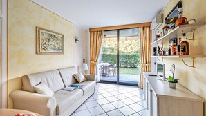 Uma sala de estar moderna com sofá, mesa de jantar e área de cozinha com prateleiras.