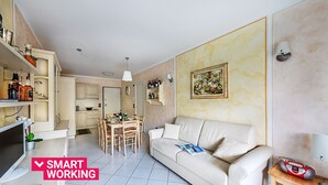Uma sala de estar moderna com sofá, mesa de jantar e área de cozinha.