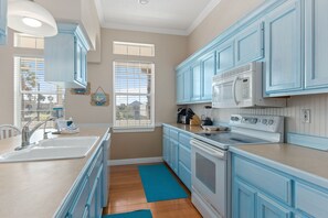 Una cocina con gabinetes azules, una estufa blanca y un fregadero.