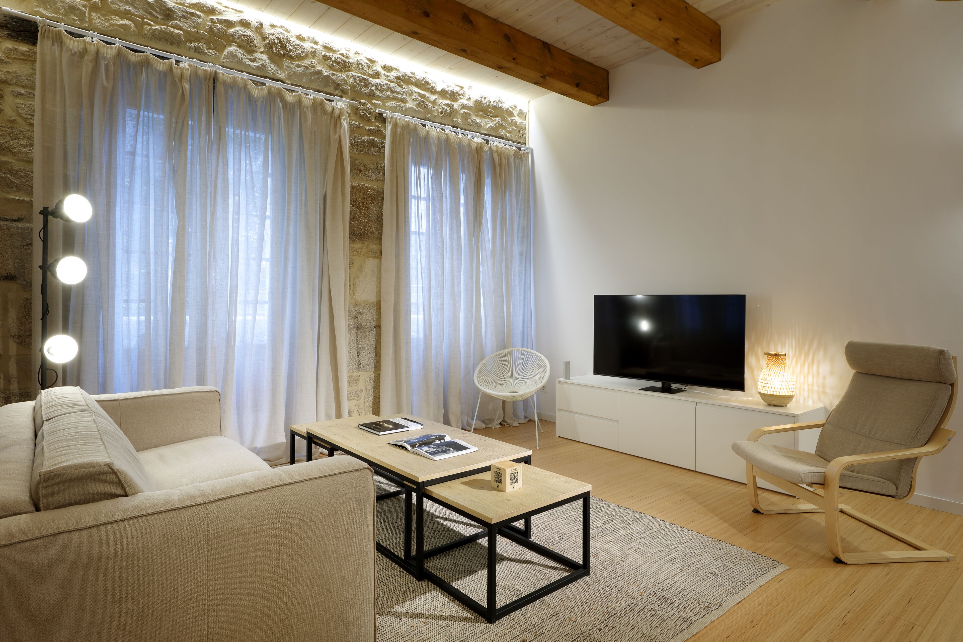 A modern living room with a sofa, a coffee table, a TV, and a chair.