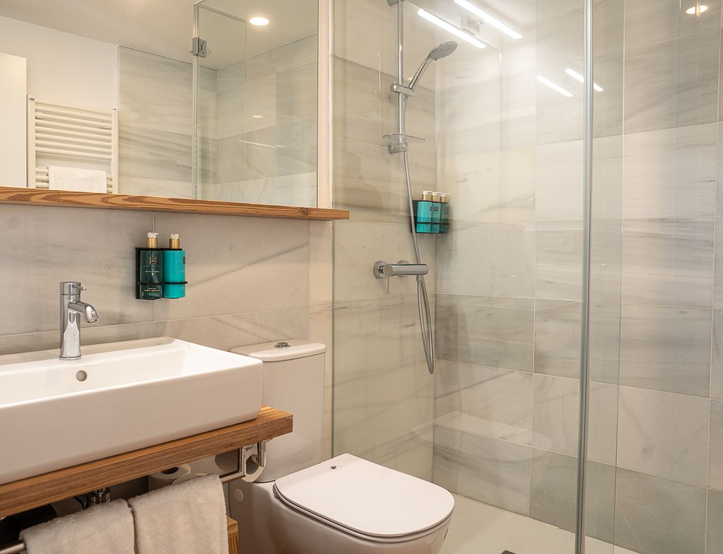 A modern bathroom with a glass shower enclosure, a white sink, and a toilet.