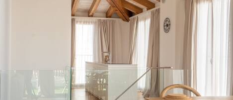 A modern interior with a wooden ceiling, a glass staircase, and a dining area with a wooden table and chairs.
