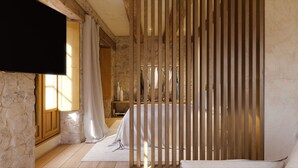 Een slaapkamer met een stenen muur, een houten bedframe en een aan de muur bevestigde televisie.