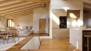 Amplia sala de estar con techo de madera, un conjunto de sofás, una mesa de comedor con sillas y una cocina con electrodomésticos integrados.