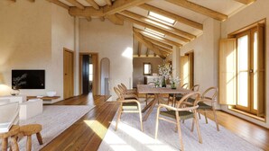 Een ruime woonkamer met een houten eettafel, stoelen en een televisie.