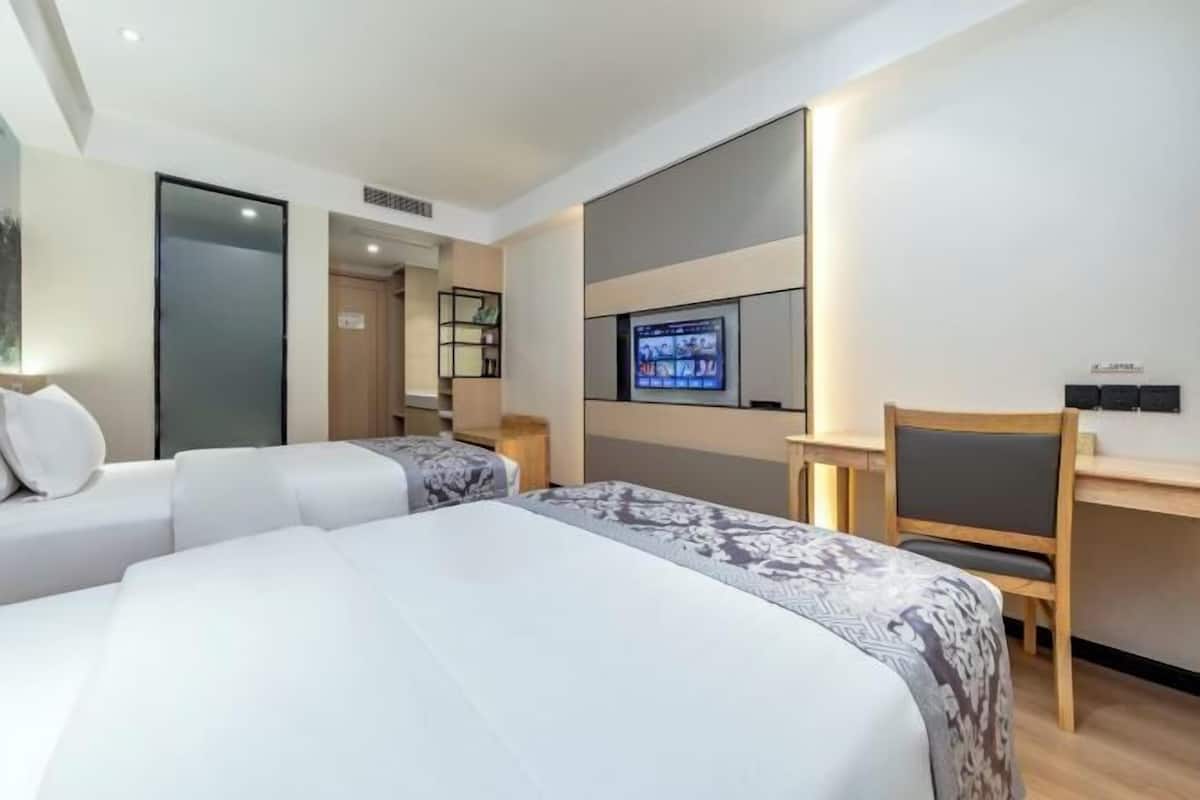 A hotel room with a bed, a desk, a TV, and a seating area.
