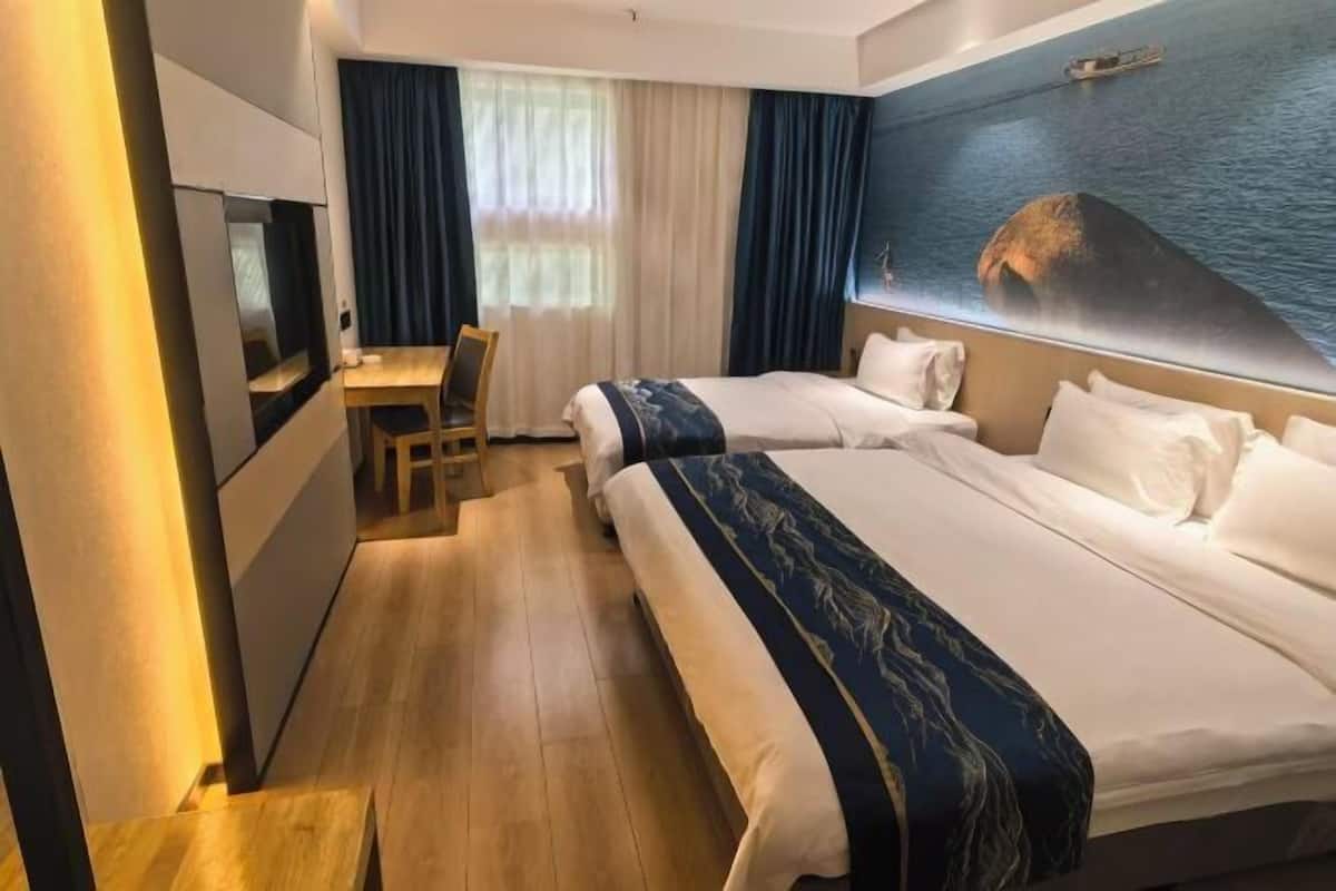 A hotel room with two beds, a desk, and a TV.